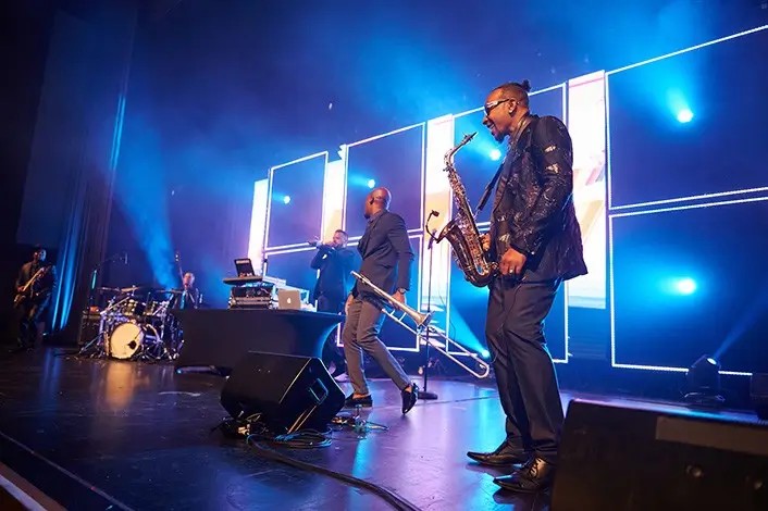 Live band performing in front of an LED wall at the House of Verizon during Super Bowl LIX